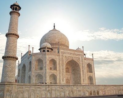 Voyage en Asie — Taj Mahal à Agra en Inde, mausolée de marbre blanc emblématique entouré de ses minarets sous un ciel clair.