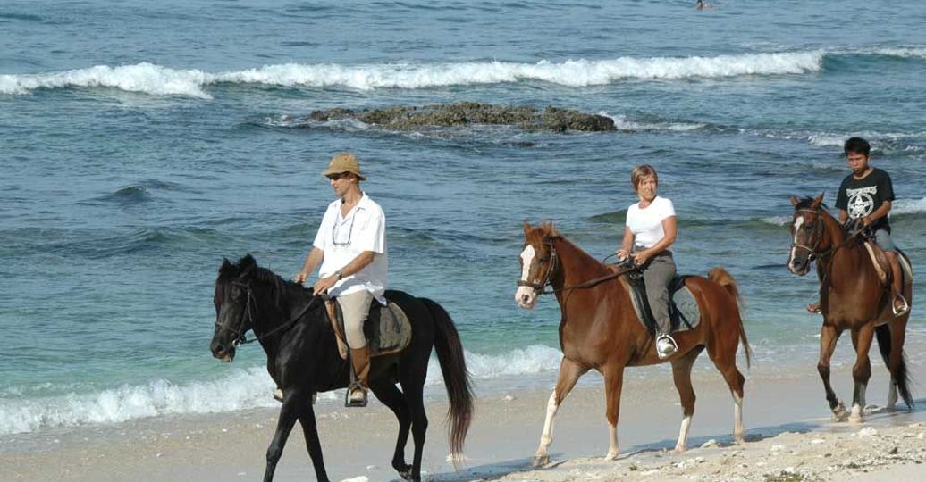 Travel in Asia - People riding horses on the beach of Lombok Island, Indonesia