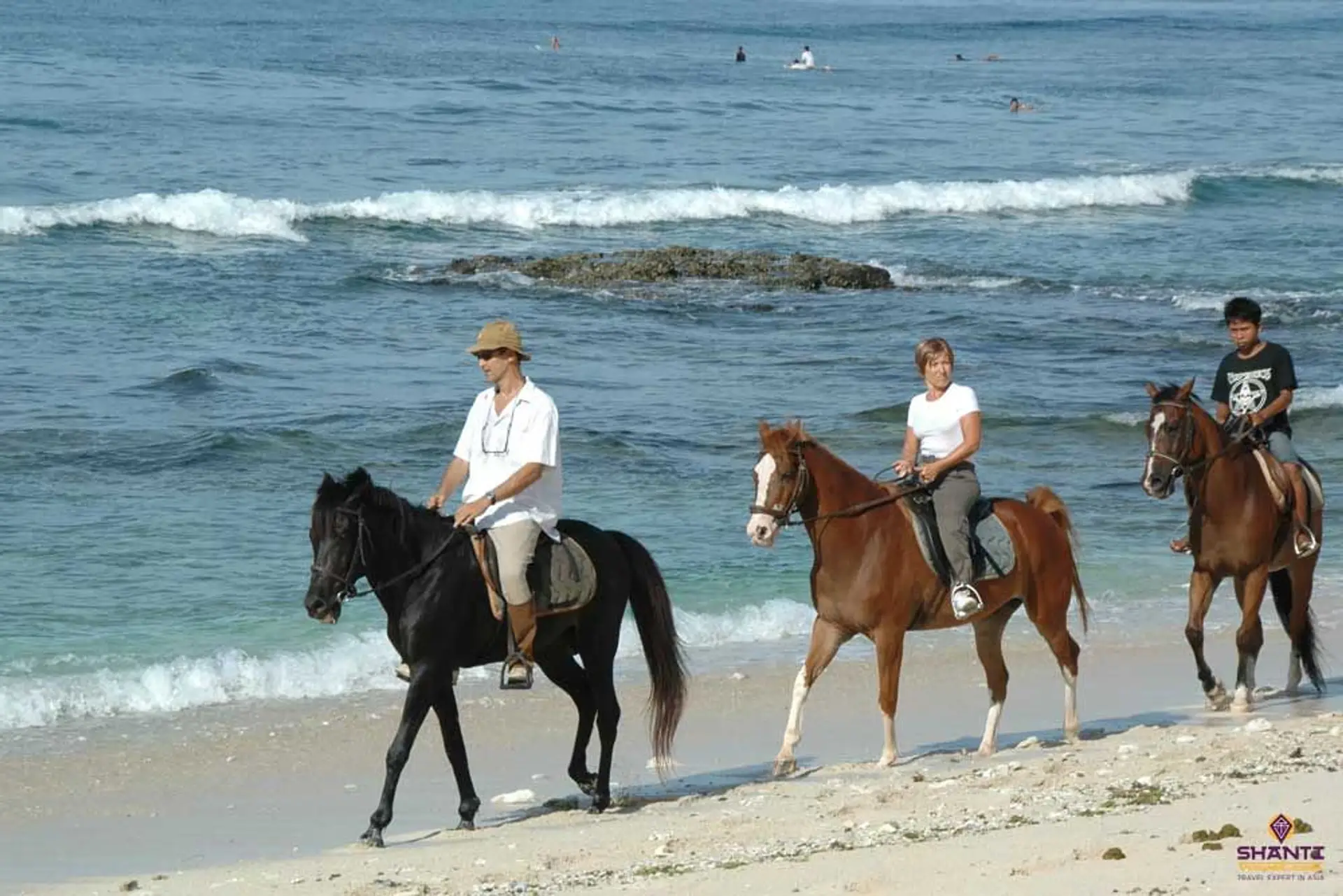Travel in Asia - People riding horses on the beach of Lombok Island, Indonesia