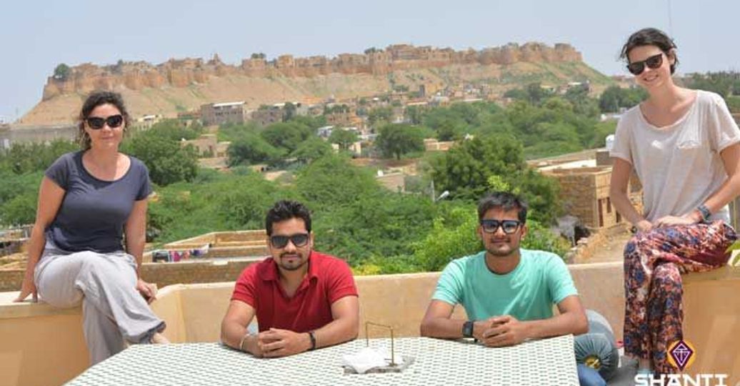 Travel in Asia - People relaxing on a rooftop in Jaisalmer, India, with a view of the historic Jaisalmer Fort in the background