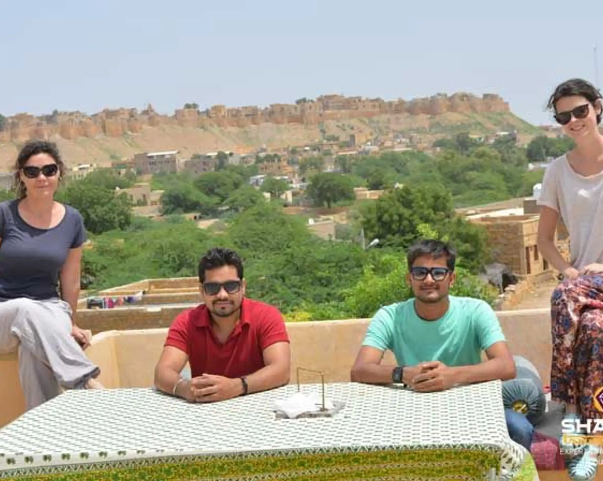 Travel in Asia - People relaxing on a rooftop in Jaisalmer, India, with a view of the historic Jaisalmer Fort in the background