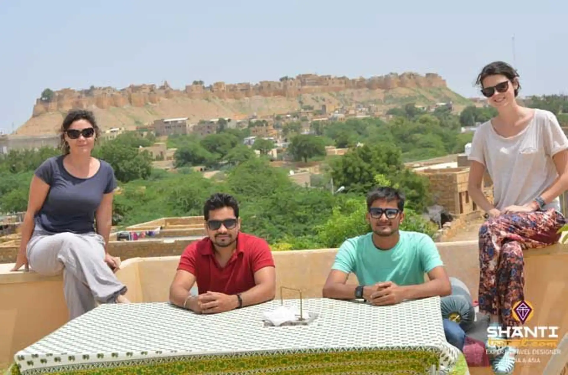 Travel in Asia - People relaxing on a rooftop in Jaisalmer, India, with a view of the historic Jaisalmer Fort in the background