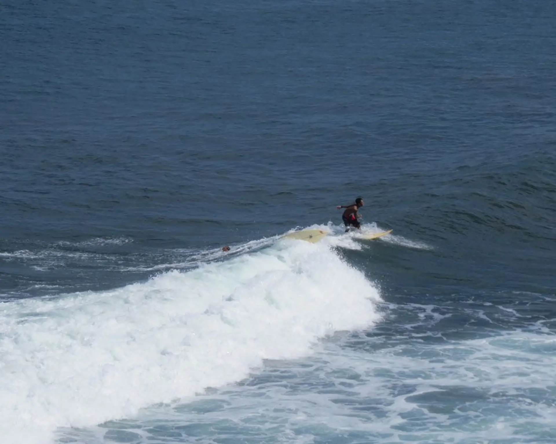 Surfeur attendant la vague au coucher du soleil sur la côte sud de Bali, silhouette sur fond d’océan et d’ambiance balinaise authentique.
