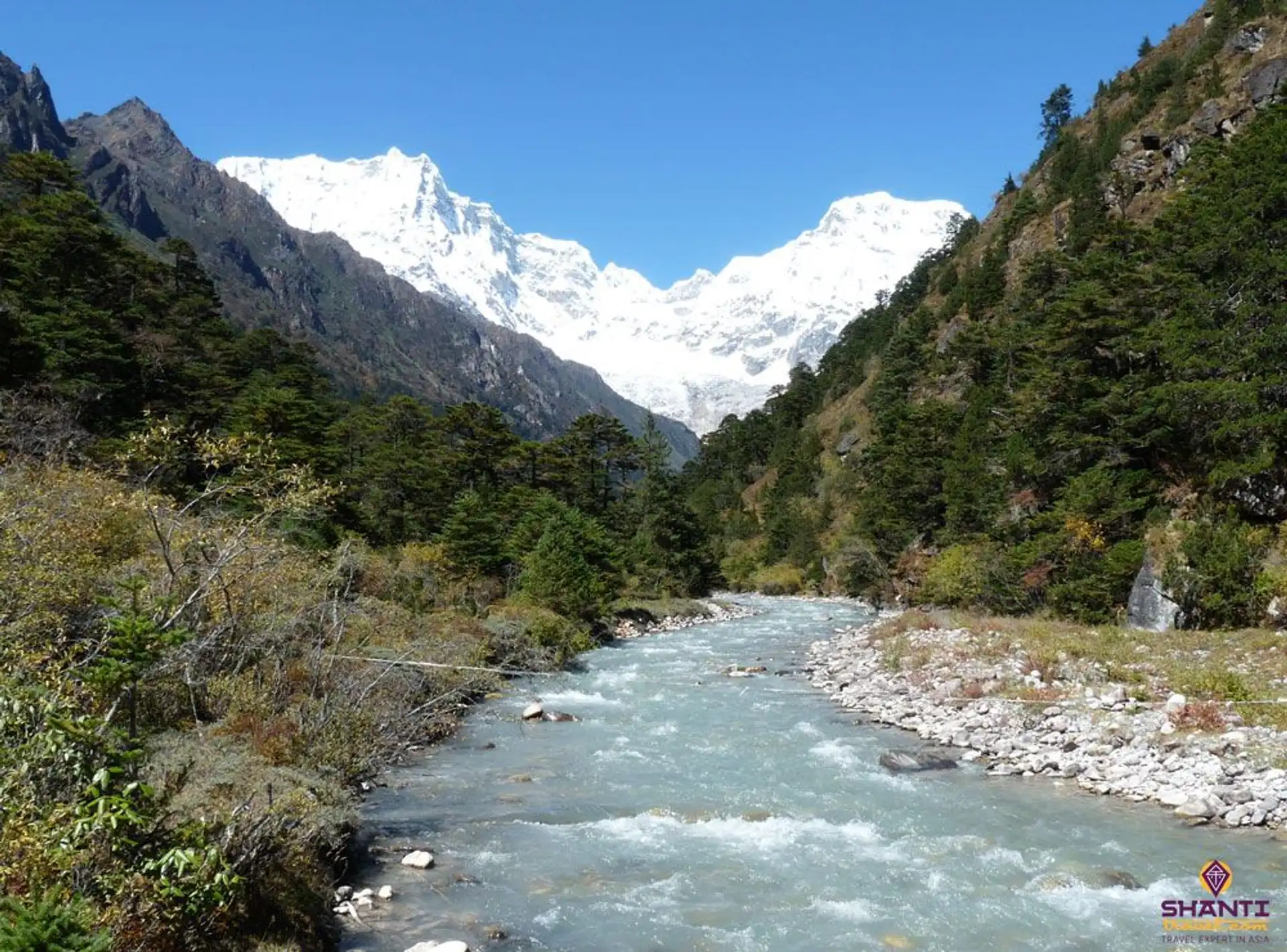 Travel in Asia - A river running through an alpine setting with snow-capped Himalayan peaks in the background