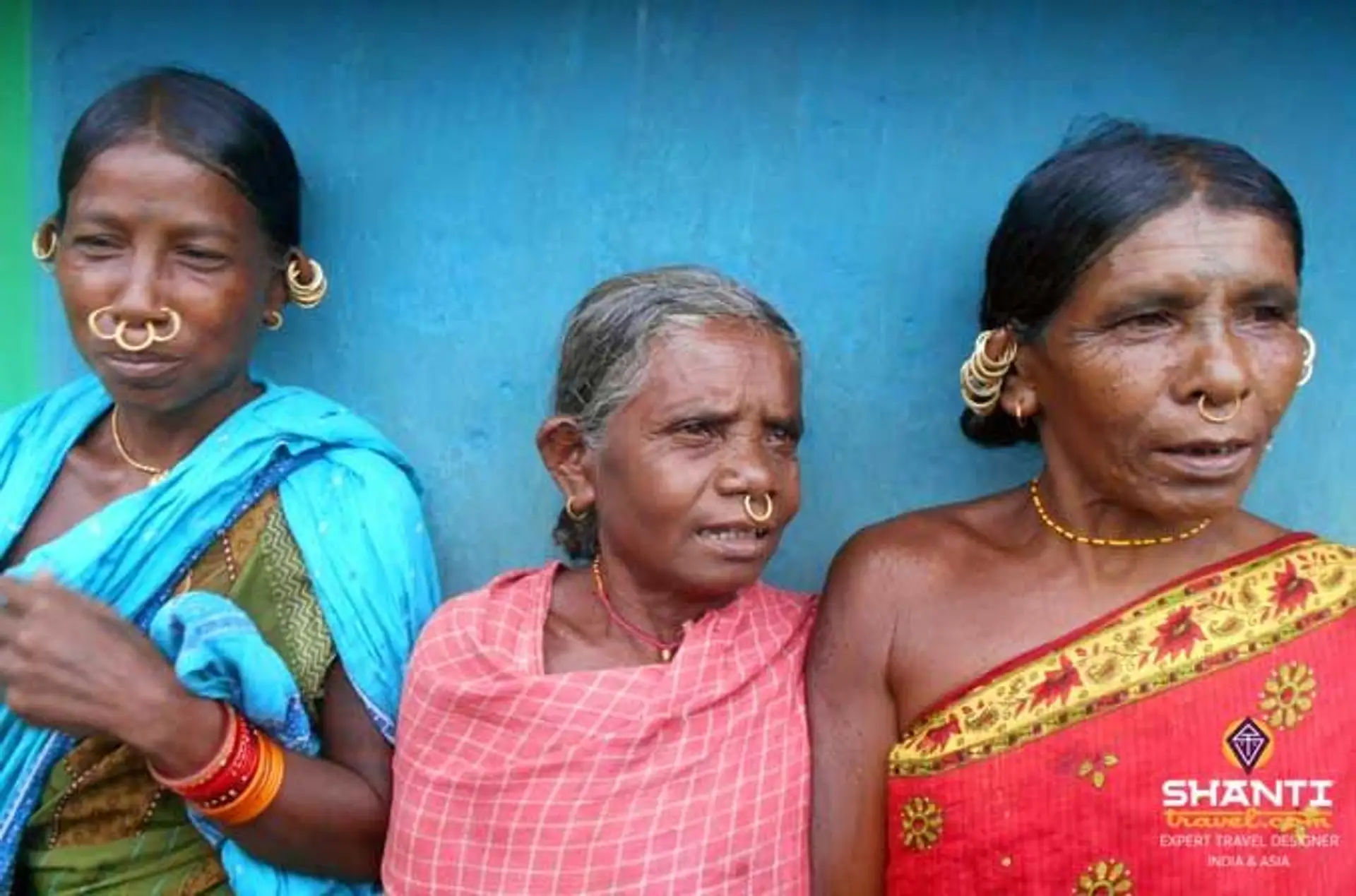 Travel in Asia - Three women standing against a blue wall in traditional clothing in Odisha