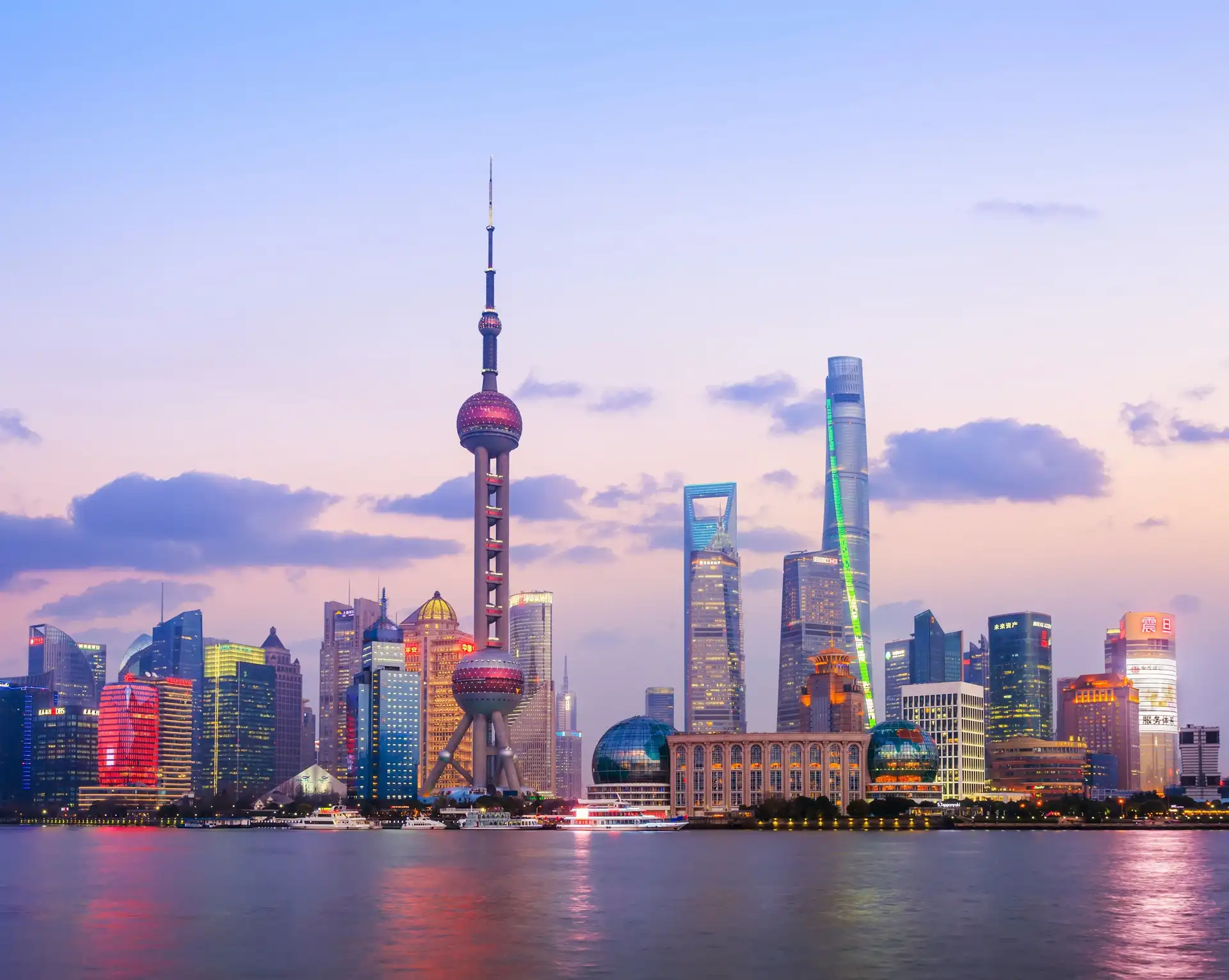 Vue panoramique iconique de la skyline de Shanghai avec la tour de la Perle de l'Orient illuminée au crépuscule depuis le Bund.