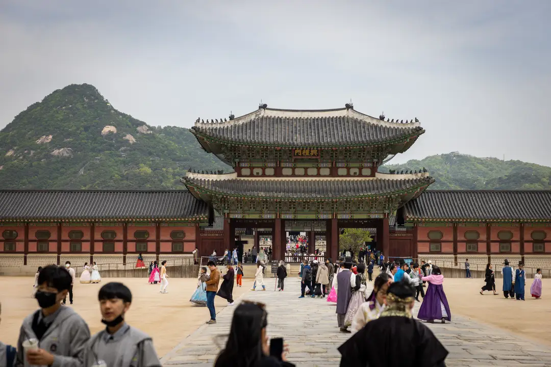 Voyage en Corée du Sud - Vue sur l’entrée du palais de Gyeongbokgung à Séoul, avec ses grandes portes et la cour de pierre qui s’étend à l’avant.