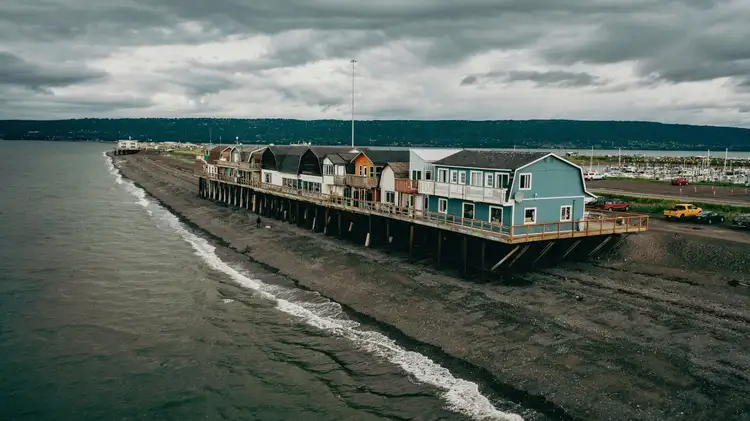 Bâtiments côtiers et maisons sur pilotis le long de la bande de terre de Homer Spit bordée par la mer et les collines en Alaska