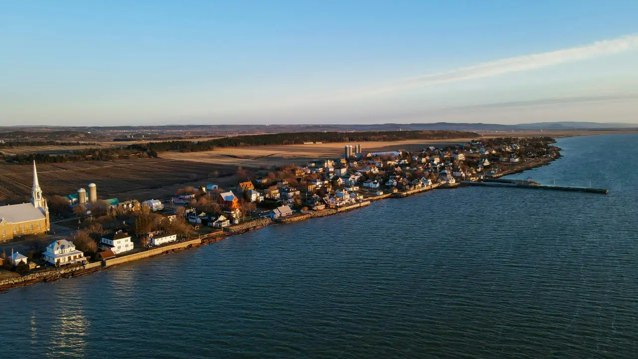Maisons patrimoniales en bois et battures verdoyantes en bordure des eaux calmes du fleuve Saint-Laurent à Kamouraska