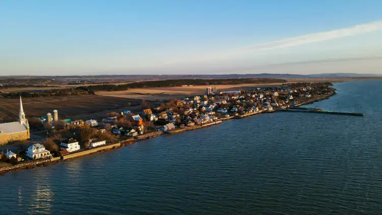 Maisons patrimoniales en bois et battures verdoyantes en bordure des eaux calmes du fleuve Saint-Laurent à Kamouraska