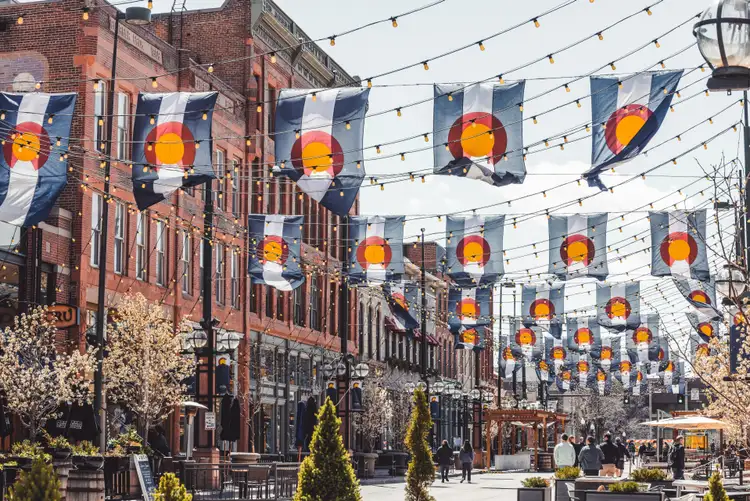 Rue historique de Larimer Square à Denver pavée et décorée de drapeaux du Colorado suspendus entre des bâtiments en briques