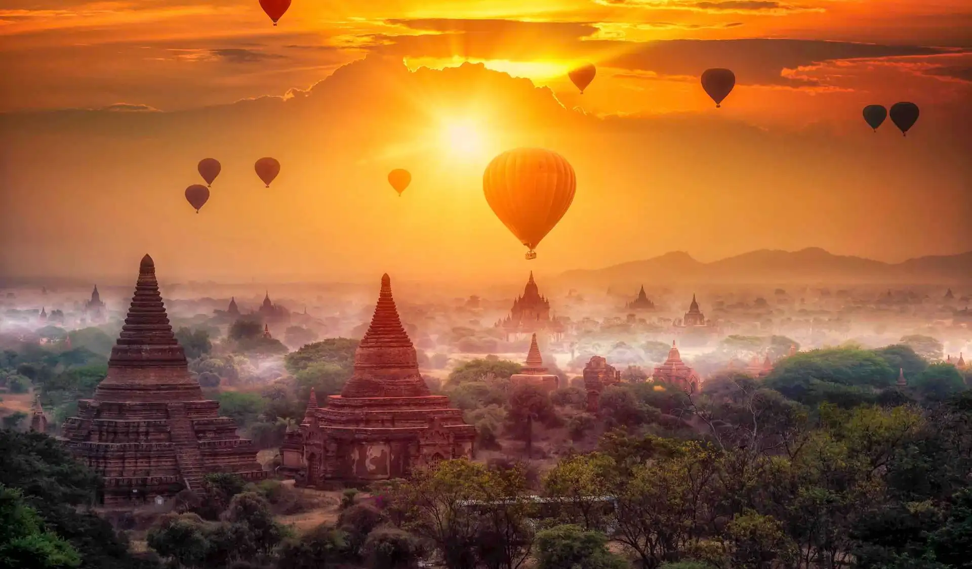 Travel in Asia - Hot air balloons rise above a temple at sunset in Myanmar (Burma)