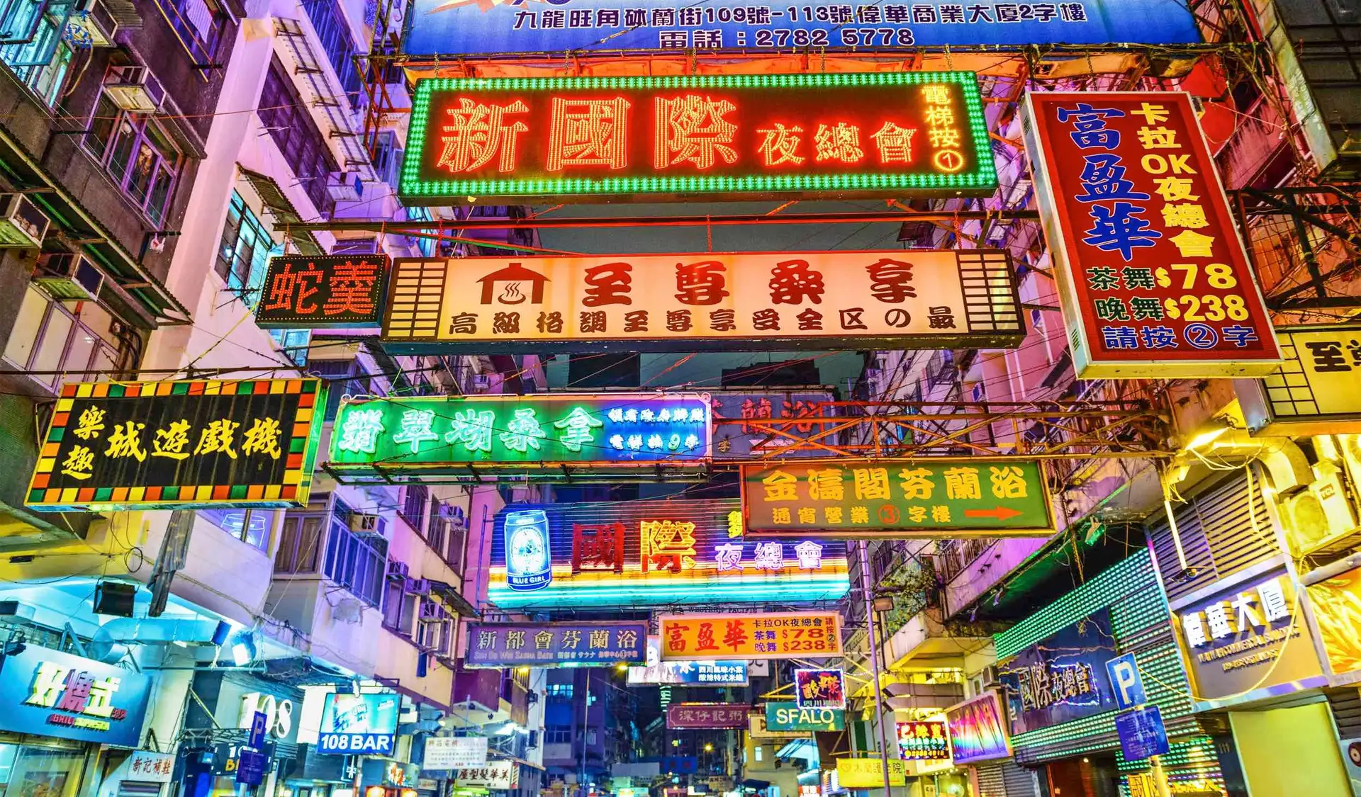 vue en contre plongee de nombreuses enseignes lumineuses et neons multicolores ecrits en caracteres chinois dans une rue animee de hong kong