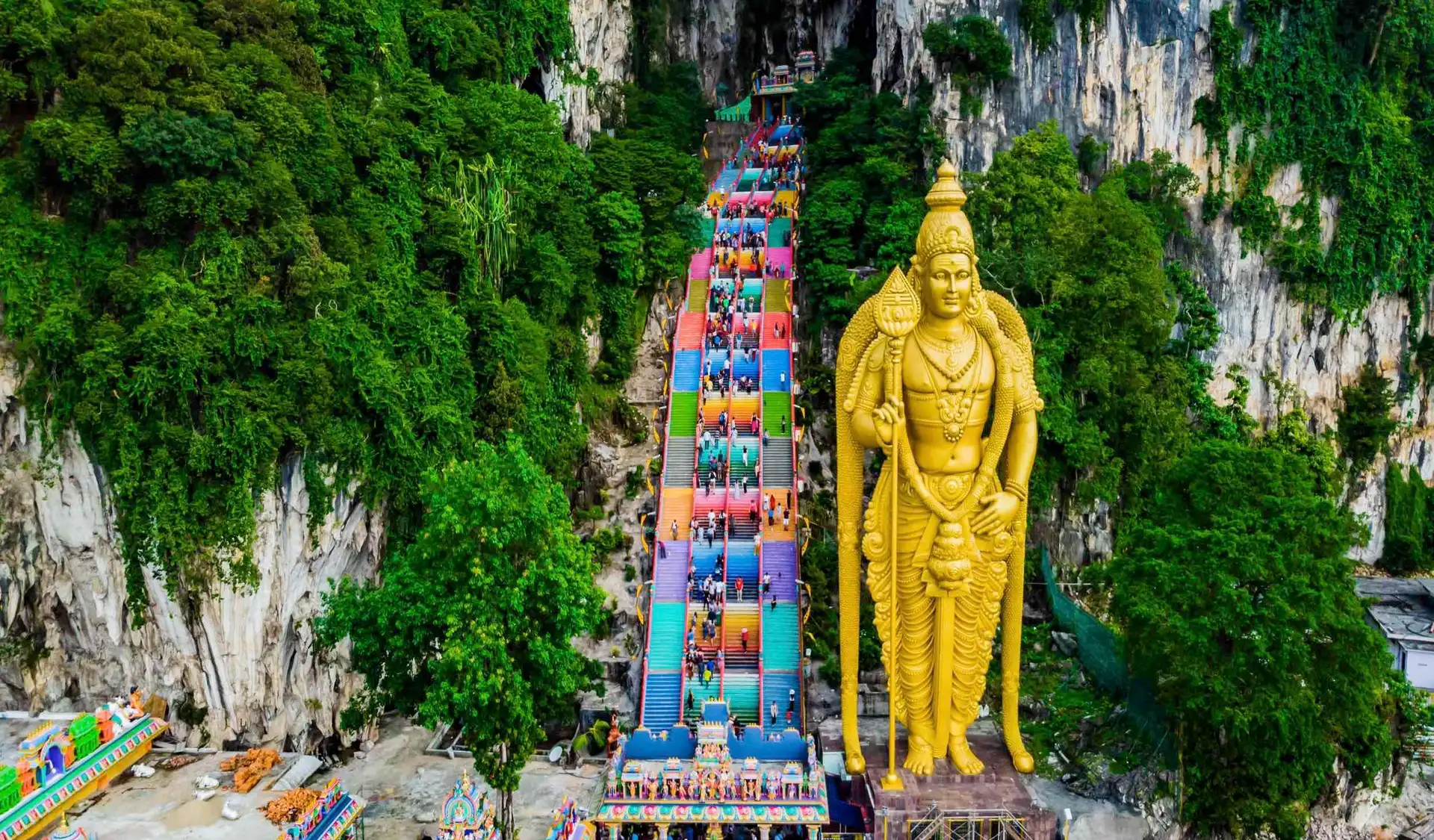 immense statue doree de lord murugan devant le grand escalier aux marches multicolores des batu caves en malaisie