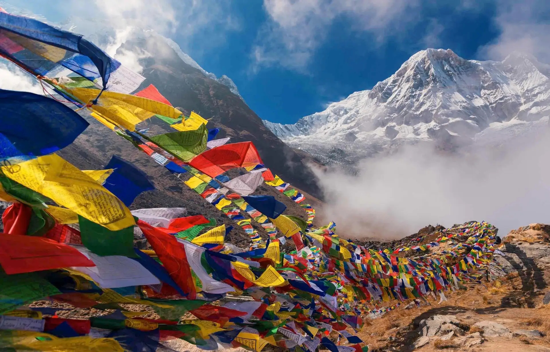 Voyage en Asie — Drapeaux de prières bouddhistes flottant dans l'Himalaya, symbole d'un trek spirituel et d'une immersion culturelle — Shanti Travel