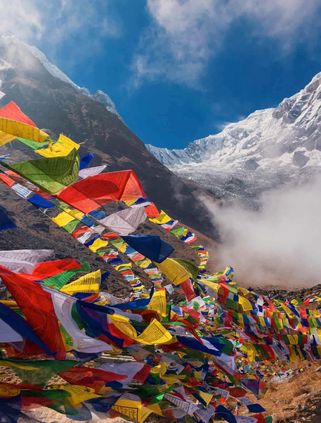 Voyage en Asie — Drapeaux de prières bouddhistes flottant dans l'Himalaya, symbole d'un trek spirituel et d'une immersion culturelle — Shanti Travel