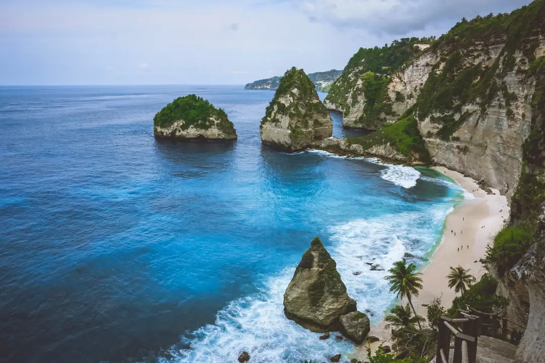 Voyage à Bali – Vue panoramique depuis les escaliers de la falaise sur l'anse sauvage de Diamond Beach, ses pitons rocheux calcaires et ses eaux turquoise à Nusa Penida.