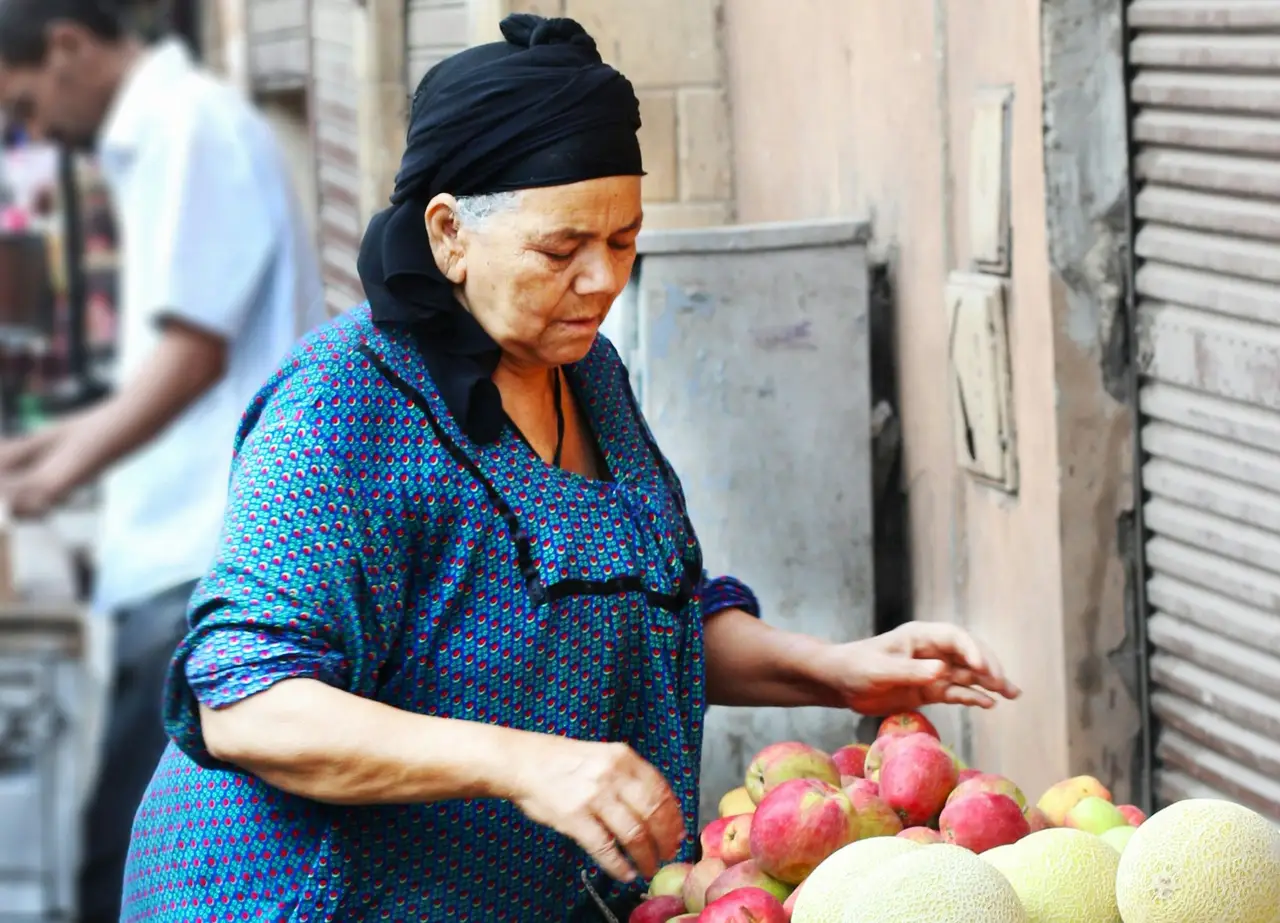Une femme égyptienne choisit des fruits sur un étal au marché