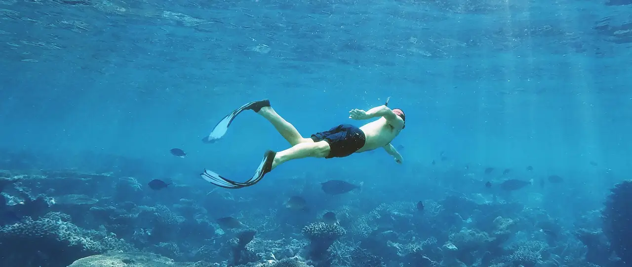 Un nageur équipé de palmes, d'un masque et d'un tuba explore les récifs coralliens dans les eaux profondes d'Hurghada