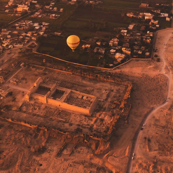 Vue aérienne au lever du soleil sur une montgolfière jaune survolant le temple funéraire de Ramsès III à Médinet Habou