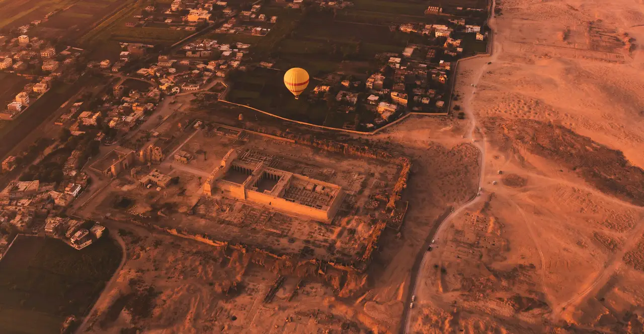 Vue aérienne au lever du soleil sur une montgolfière jaune survolant le temple funéraire de Ramsès III à Médinet Habou