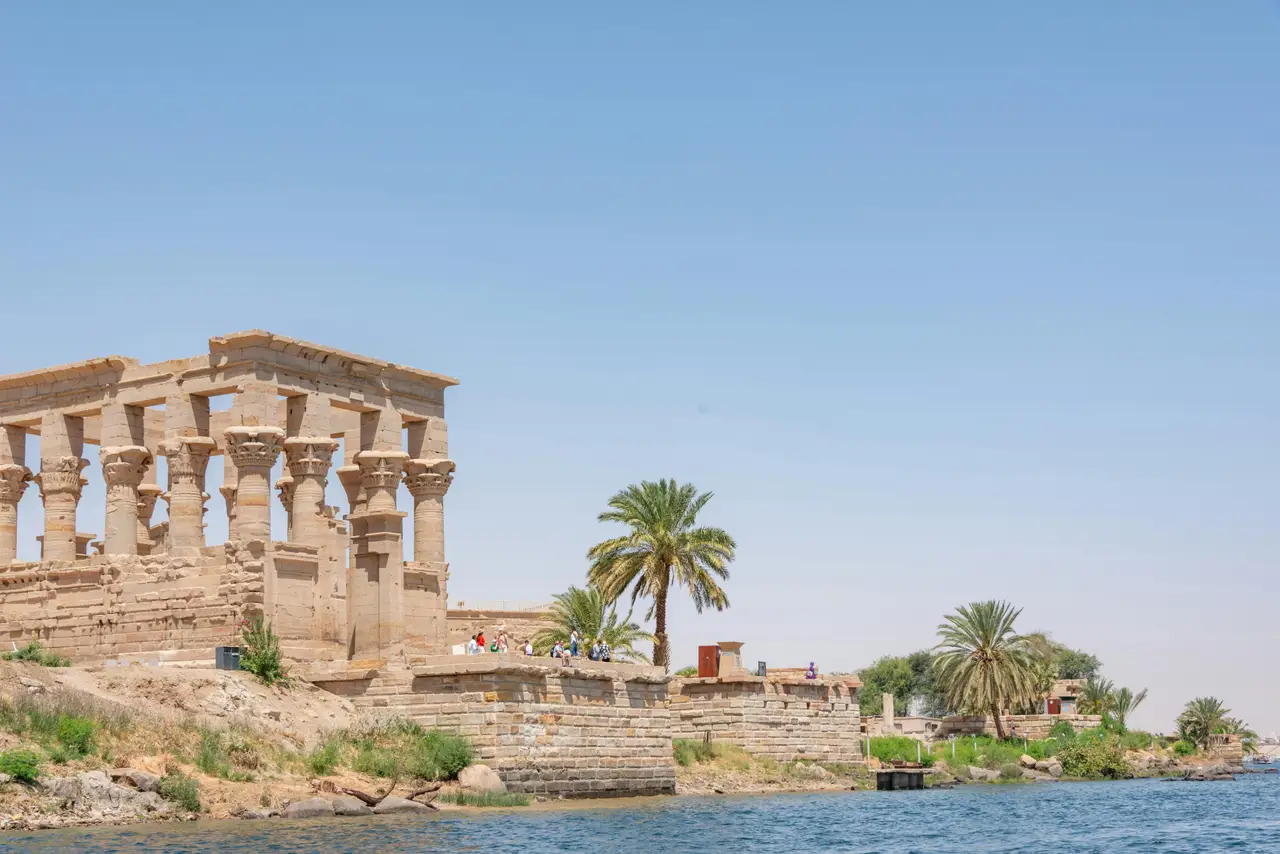 Le kiosque de Trajan et les structures du temple de Philae bordant les eaux du Nil sous un ciel clair
