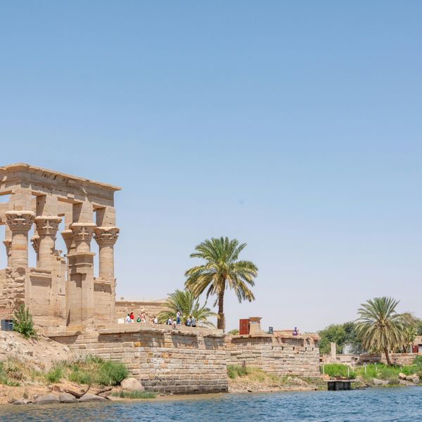 Le kiosque de Trajan et les structures du temple de Philae bordant les eaux du Nil sous un ciel clair