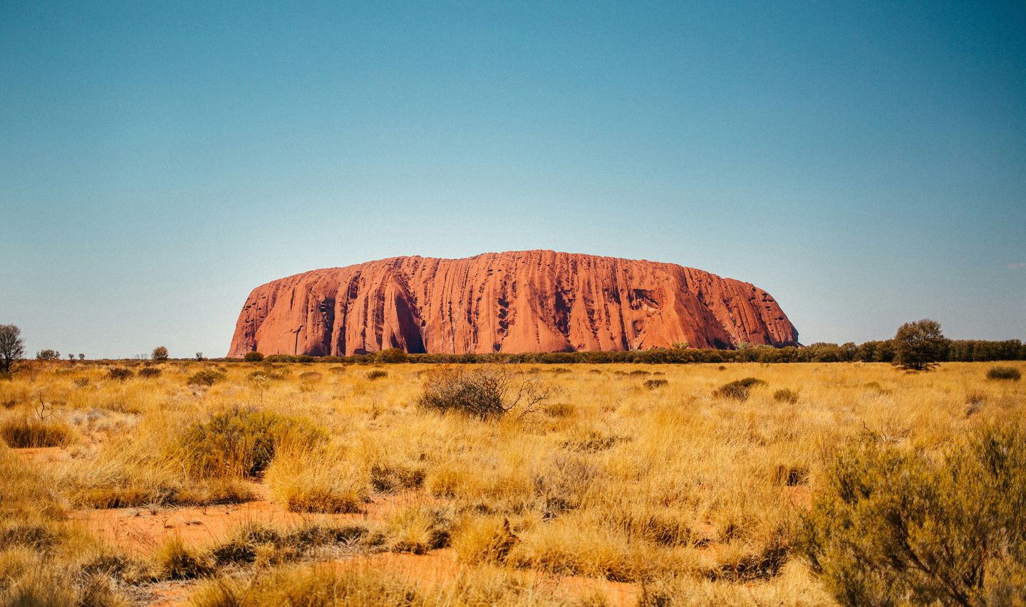 Panorama sauvage sur l'imposant monolithe rouge d'Uluru, symbole australien