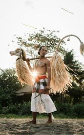 Voyage en Asie — Danseur balinais portant un masque et des accessoires traditionnels : silhouette en contre-jour et ambiance rituelle.
