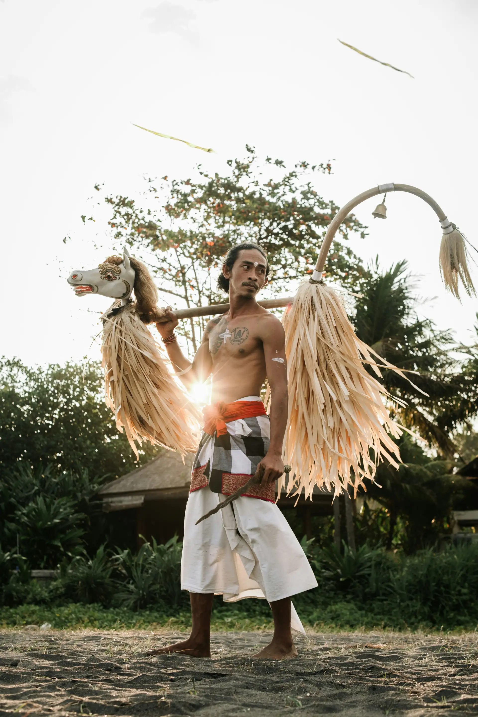 Voyage en Asie — Danseur balinais portant un masque et des accessoires traditionnels : silhouette en contre-jour et ambiance rituelle.
