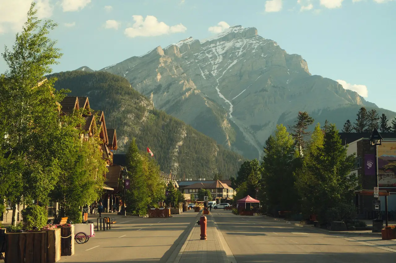 Avenue principale de la ville de Banff bordée d'arbres et de bâtiments avec la silhouette imposante du mont Cascade à l'arrière-plan