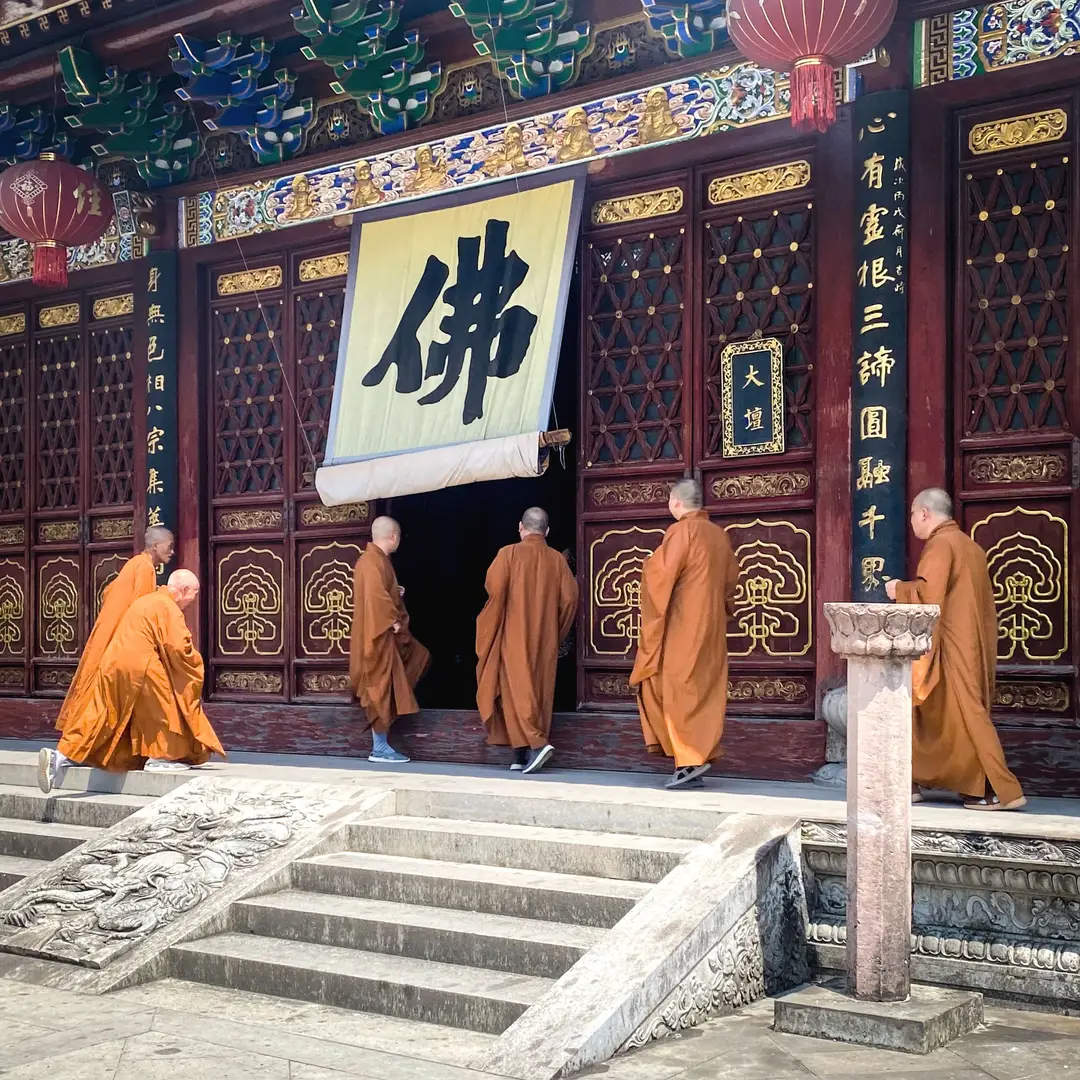 groupe de moines bouddhistes en robes orange entrant dans un temple orné avec une architecture traditionnelle..jpg