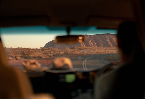 Route goudronnée menant au rocher sacré d'Uluru sous le soleil