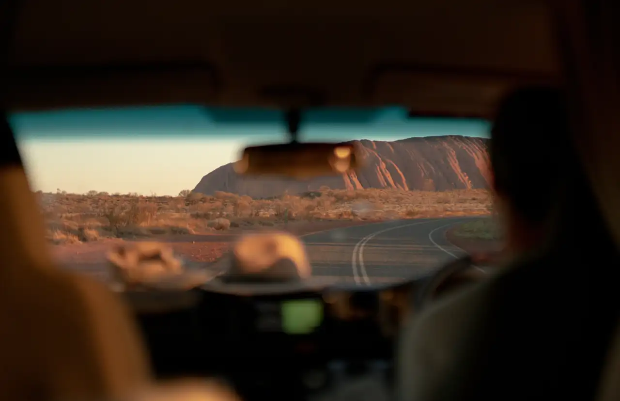 Route goudronnée menant au rocher sacré d'Uluru sous le soleil