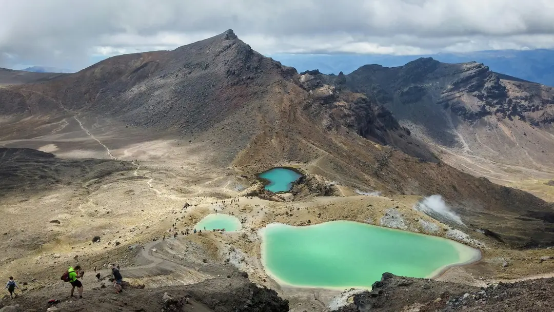 Randonneurs surplombant les lacs Émeraude au cœur des paysages volcaniques du Tongariro, en Nouvelle-Zélande