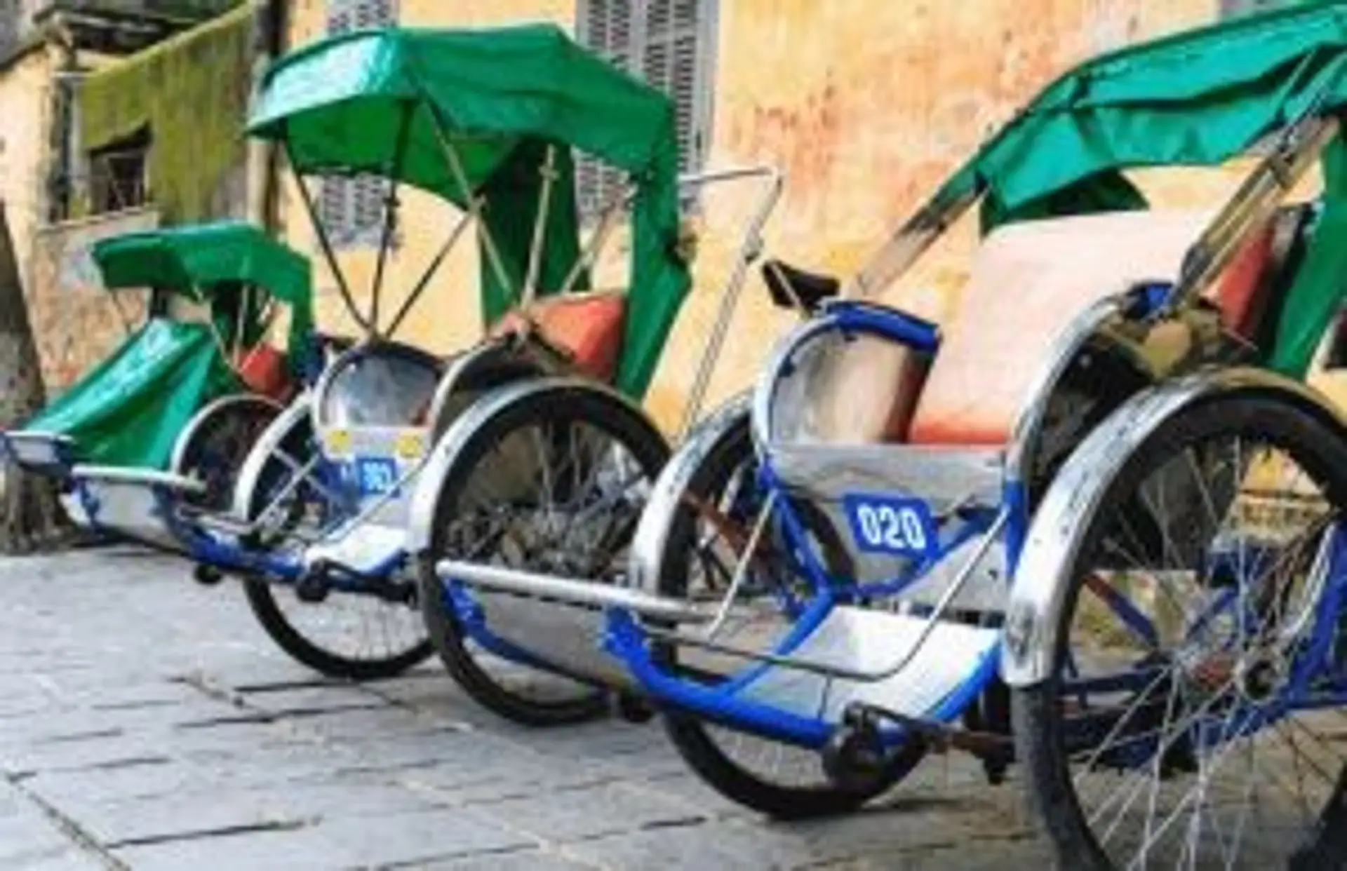 Travel in Asia - Three rickshaws parked against a wall in Vietnam