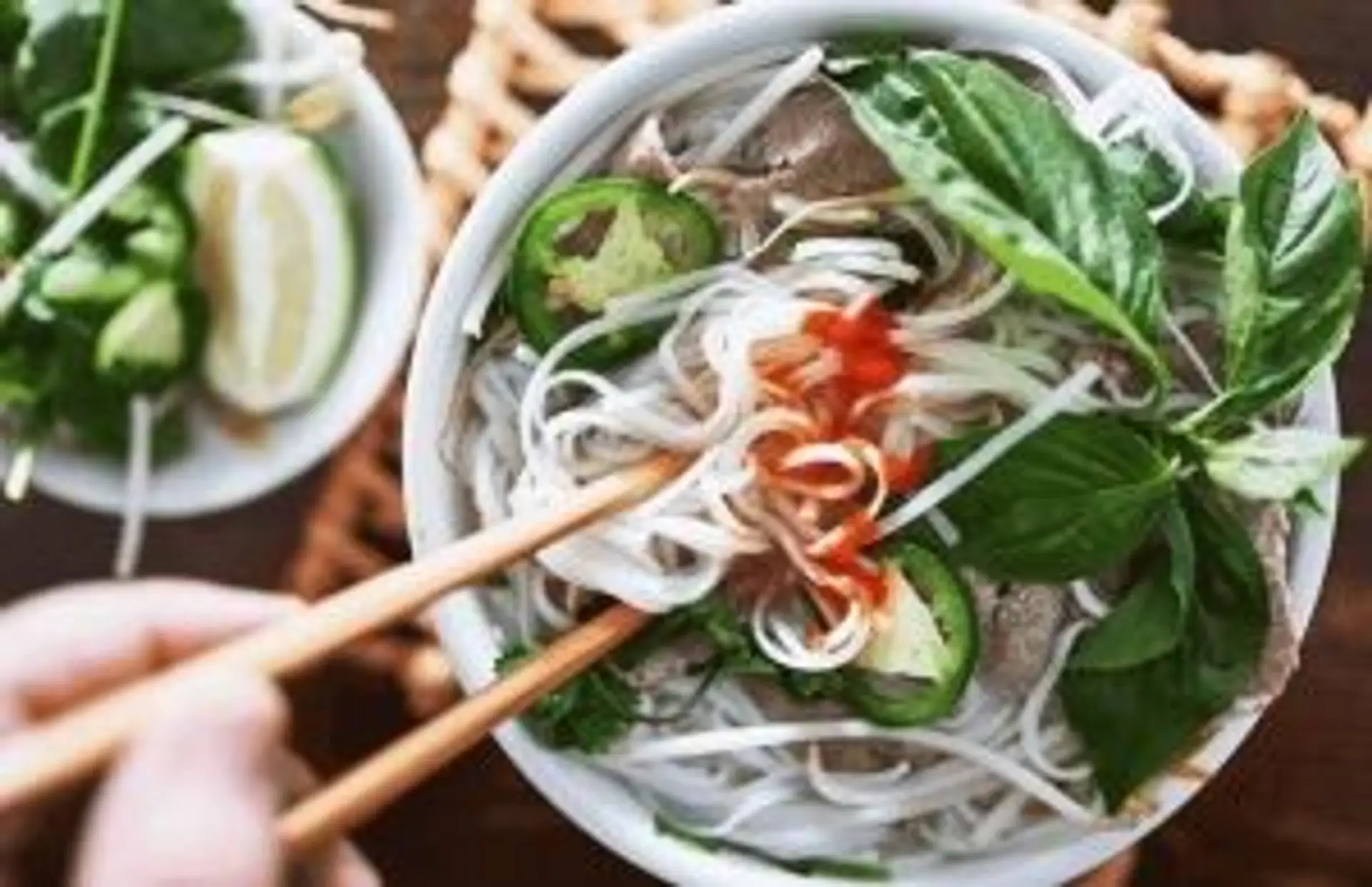 Travel in Asia - A person's chopsticks entering a bowl of pho with plenty of toppings