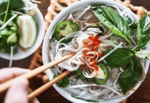 Travel in Asia - A person's chopsticks entering a bowl of pho with plenty of toppings
