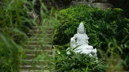 Statue de divinité bouddhiste en pierre blanche dans un jardin zen luxuriant en Chine