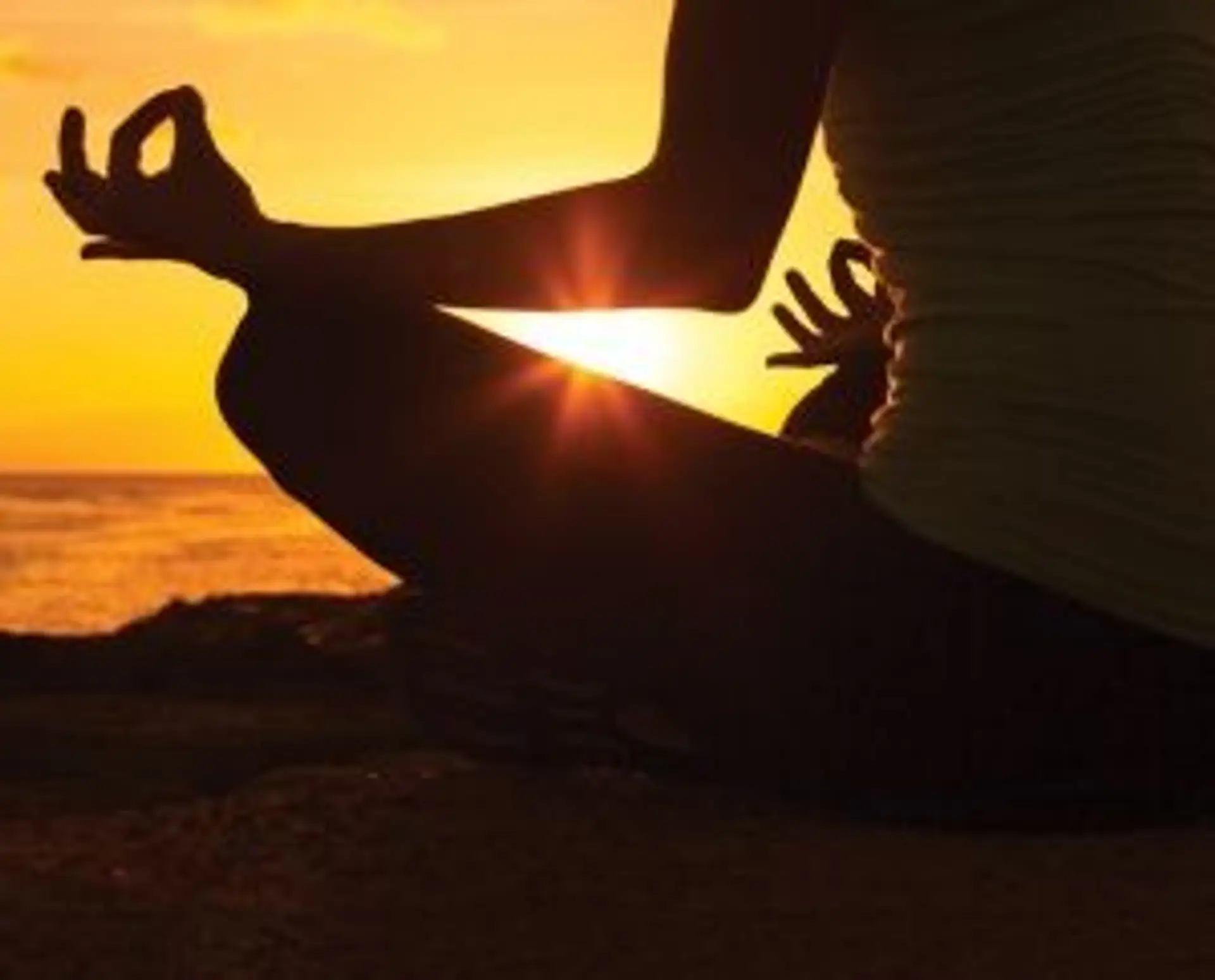 Travel in Asia - Person sitting in a meditative yoga pose, silhouetted against a sunset over water.