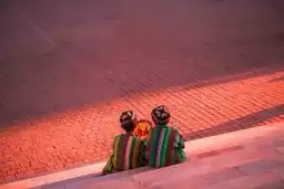 Voyage en Ouzbékistan — Deux hommes en costume traditionnel discutant sur les marches d'un monument au coucher du soleil.