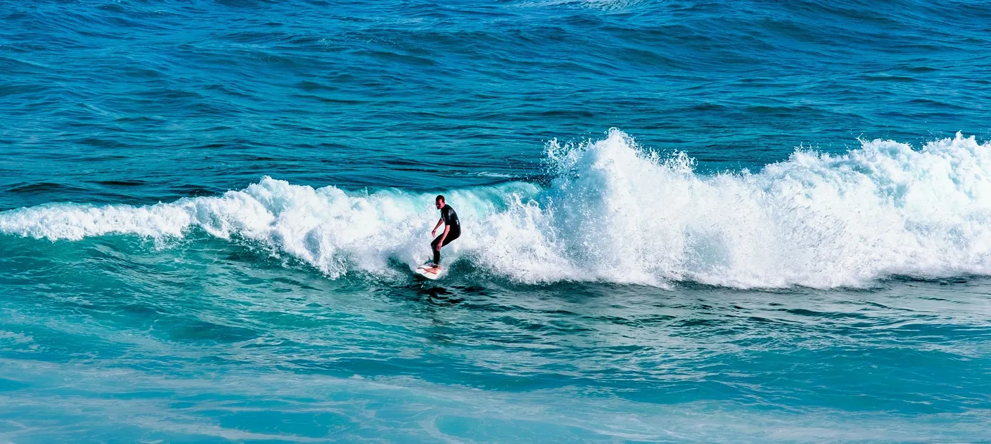 Surfeur en pleine action glissant sur une vague puissante dans les eaux turquoise de l'océan