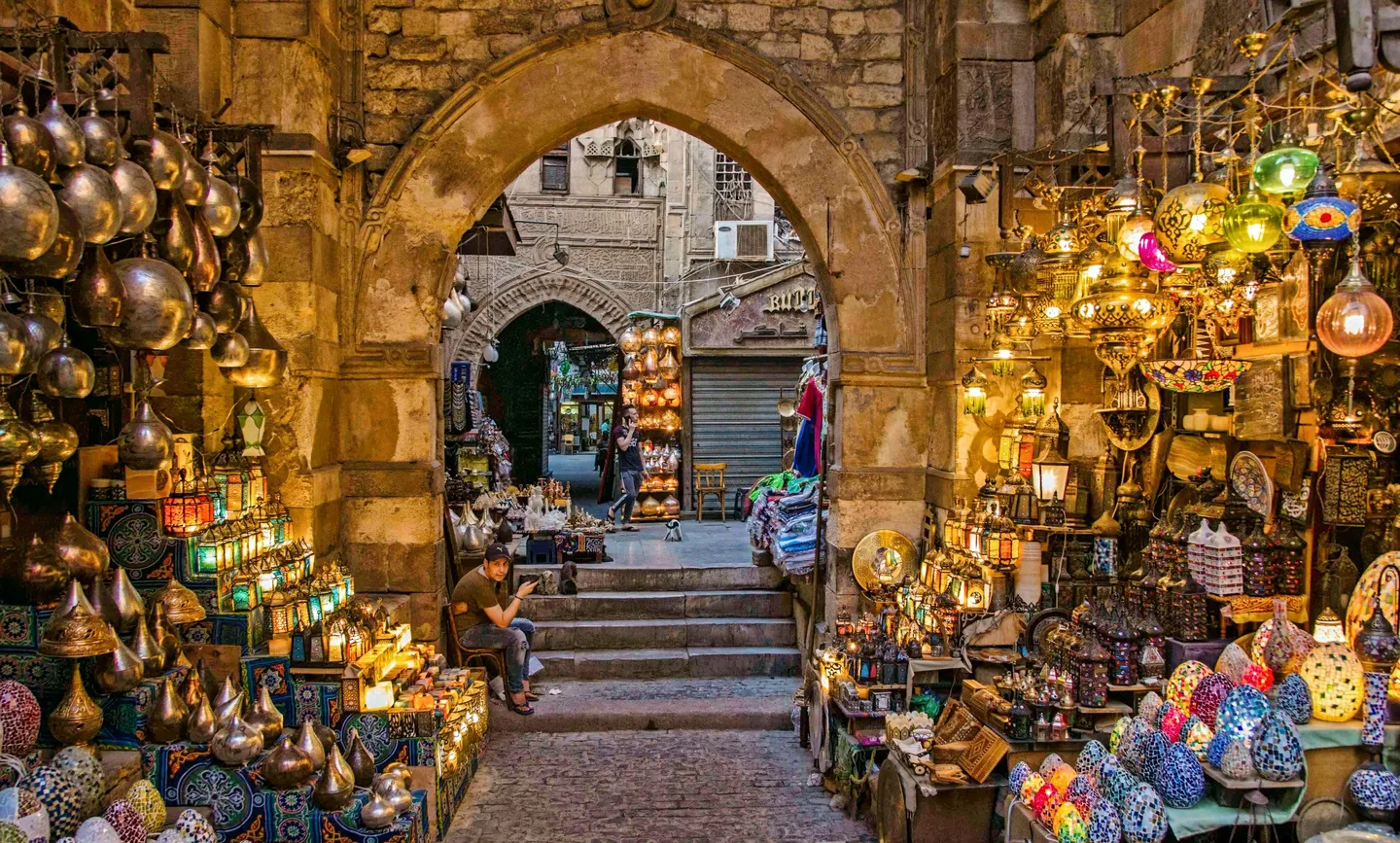 Voyage en Égypte – ruelle de souk bordée d’échoppes de lanternes artisanales sous des arches en pierre