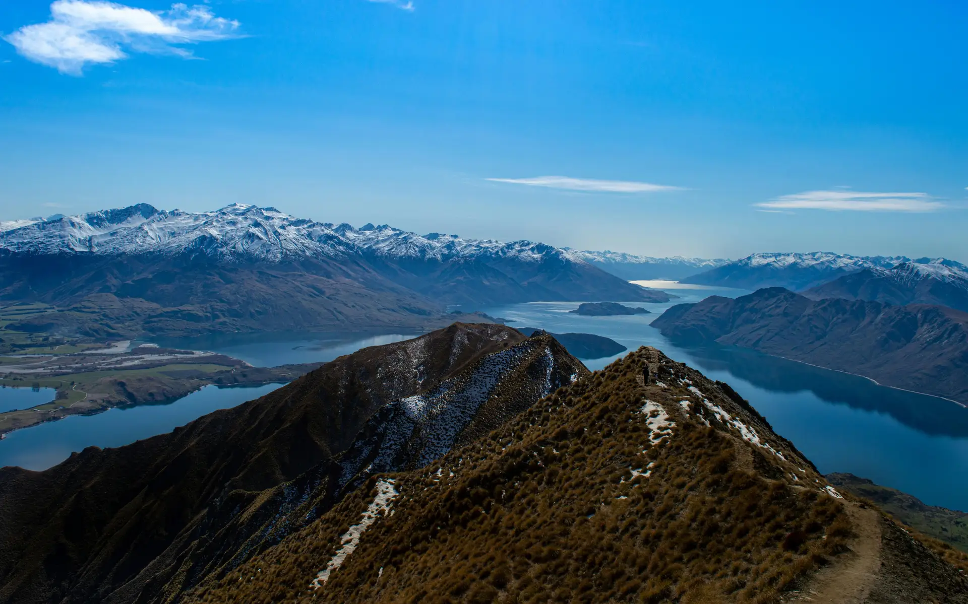 Vue panoramique depuis un sentier de crête sur un lac et des montagnes enneigées en Nouvelle-Zélande.