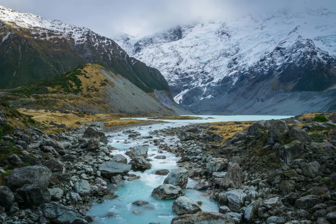 Rivière glaciaire turquoise s'écoulant au pied du Mont Cook enneigé