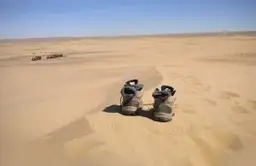 Chaussures de trekking posées sur une crête de dune dans le désert de Gobi, illustrant l'aventure en Mongolie.