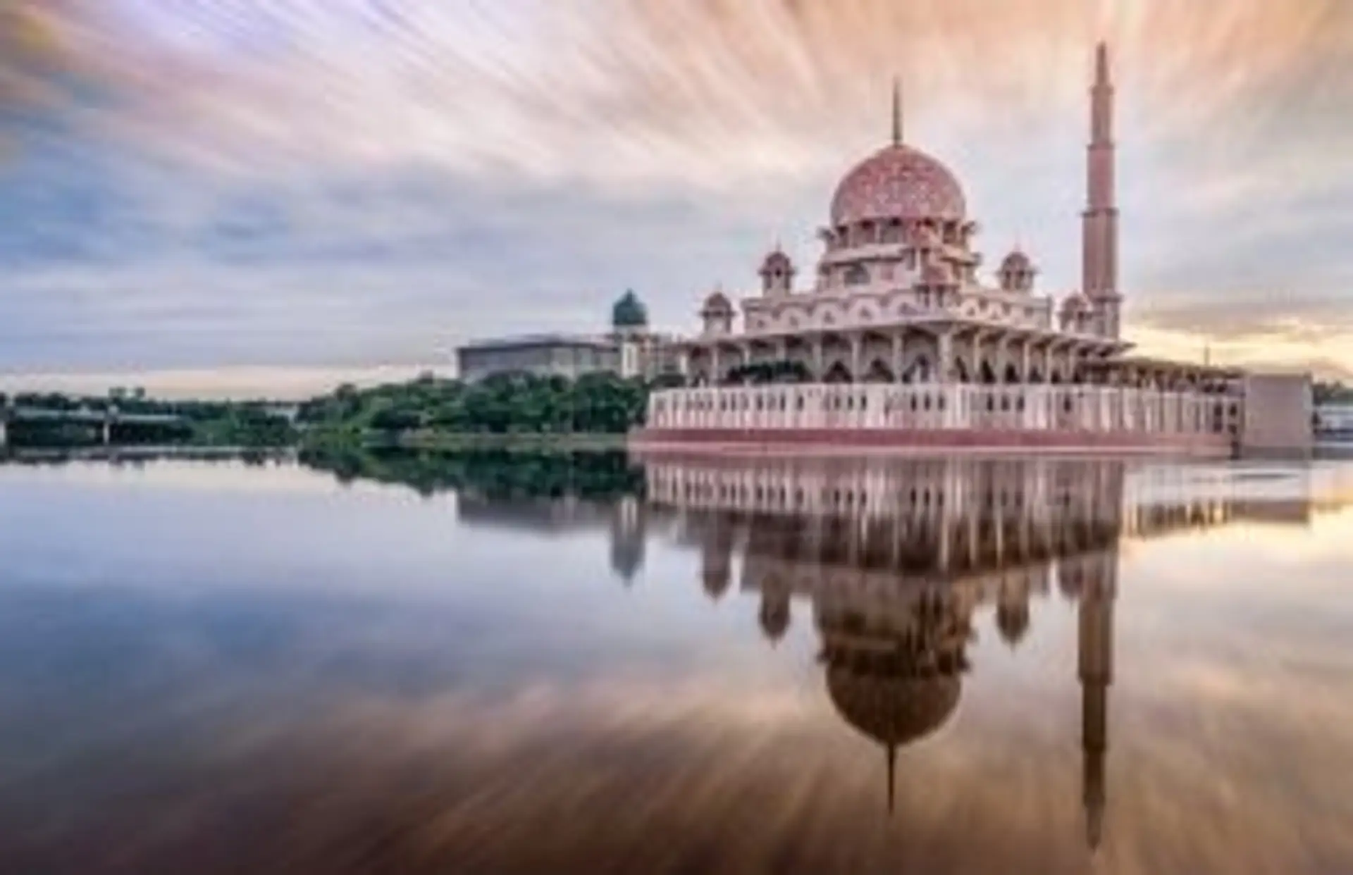Mosquée Putra rose et son reflet sur l'eau au coucher du soleil à Putrajaya en Malaisie