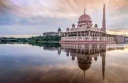 Mosquée Putra rose et son reflet sur l'eau au coucher du soleil à Putrajaya en Malaisie