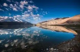 Reflet parfait des montagnes et des nuages sur les eaux turquoise du lac Bulunkul dans le Pamir au Tadjikistan