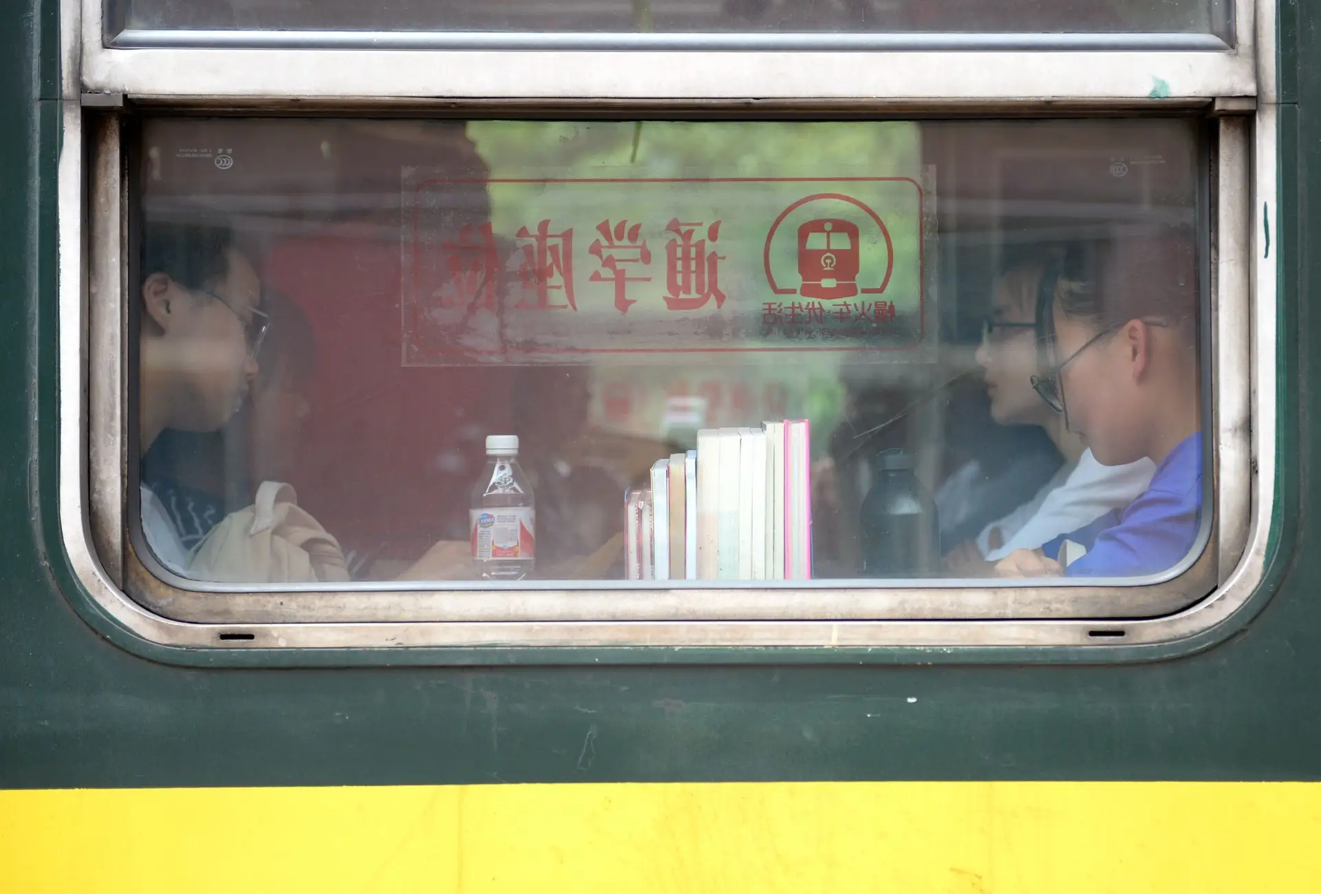 Voyager en train en Chine – Passagers assis à bord d'un train traditionnel chinois vus de l'extérieur par la fenêtre.